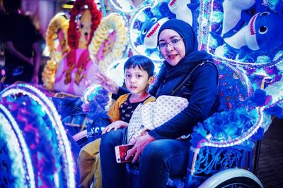 Portrait of smiling mother and son sitting on chair