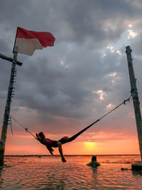 Silhouette people by sea against sky during sunset