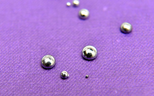 Close up of shiny drops on purple fabric