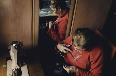 High angle view of senior woman stitching at home