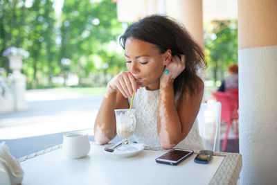 Young woman drinking coffee at table