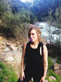 Portrait of smiling young woman standing in forest