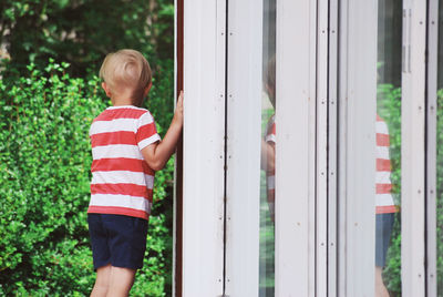 Rear view of boy standing by window