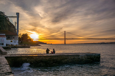 Suspension bridge over sea during sunset
