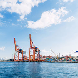 Cranes at commercial dock against sky