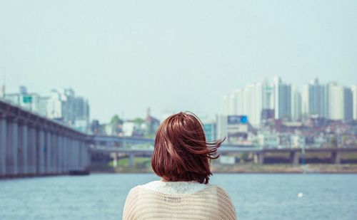 Rear view of woman looking at cityscape against clear sky