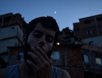 Portrait of young man against building at dusk