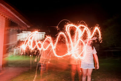 Blurred motion of woman making light painting at night