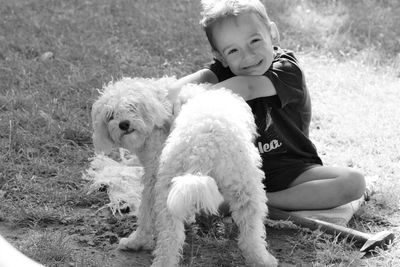 Portrait of smiling boy with dog sitting on land