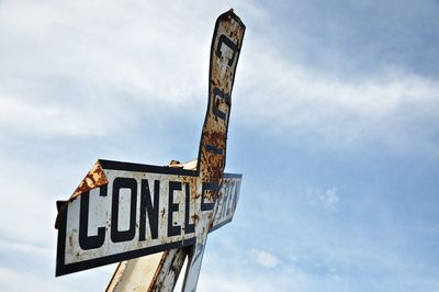 Low angle view of damaged information sign against sky