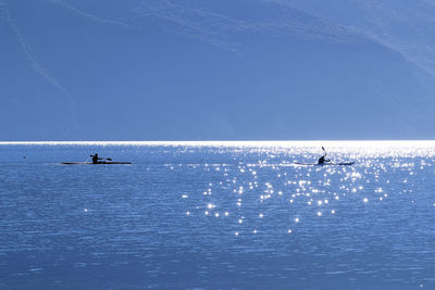 Silhouette people in sea against sky