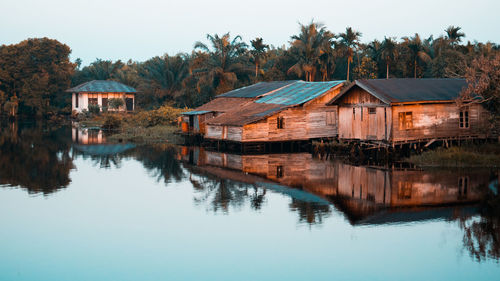 Reflection of trees and houses on lake against sky