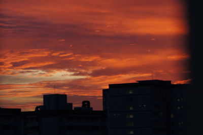 Silhouette city against orange sky