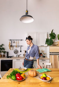 Young and beautiful housewife woman cooking in a white kitchen