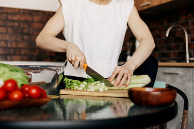 Girl cuts celery while preparing salad in the kitchen