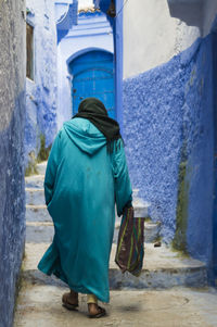 Rear view of people walking on footpath amidst buildings