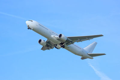 Low angle view of airplane flying against clear blue sky