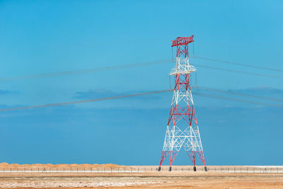 Low angle view of electricity pylon against blue sky