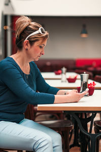 Woman using mobile phone while sitting on table