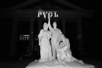 Statue of buddha against building at night