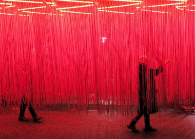 Digital composite image of people standing against illuminated red lights