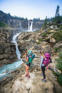 Two hikers admiring twin falls waterfall in yoho national park