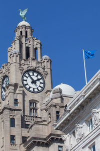 Low angle view of clock tower against blue sky