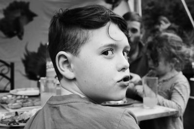 Rear view portrait of boy having food on table