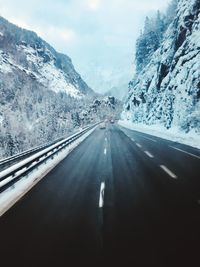 Cars on road amidst snowcapped mountains during winter