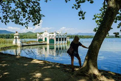 Rear view of woman standing against historic building in lake