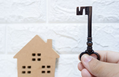 Close-up of hand holding wooden house against building