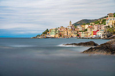 Buildings by sea against sky