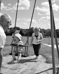 Grandparents enjoying with baby swinging at playground