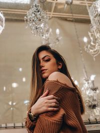 Portrait of beautiful young woman standing against ceiling