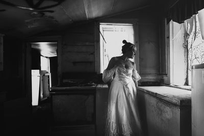 Portrait of young woman standing by window