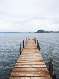 Wooden jetty on pier over sea against sky