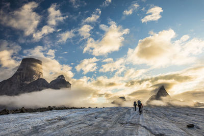 People on snowcapped mountain against sky