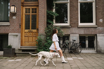 Side view of woman with dogs in front of house