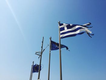 Low angle view of greek and european flags against clear blue sky