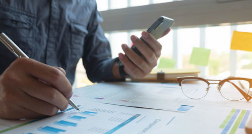 Midsection of man using mobile phone on table