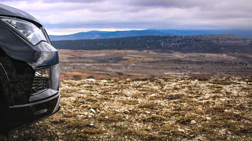 Close-up of car on landscape against sky