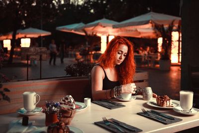 Portrait of young woman using laptop in restaurant