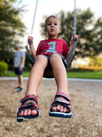 Low section of a boy swinging on swing