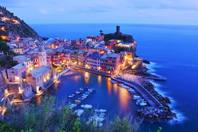 High angle view of illuminated city by sea