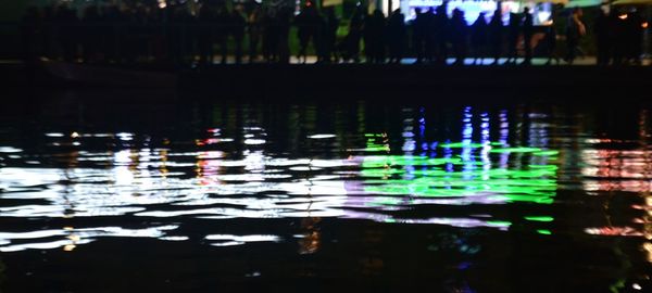 Reflection of illuminated trees in lake at night