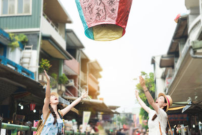 Young woman with friend looking at lantern in mid-air