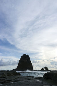 Rock formation on beach against sky