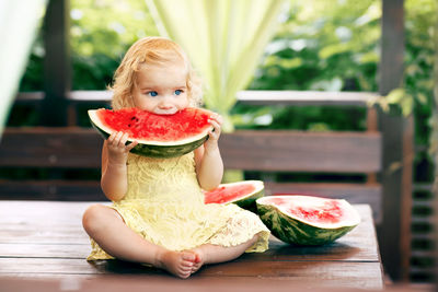 Portrait of girl eating fruit on table