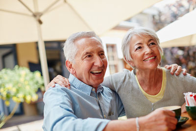 Happy senior man and woman sitting in sidewalk cafe