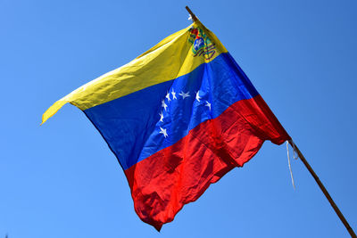 Low angle view of venezuelan flag against clear blue sky